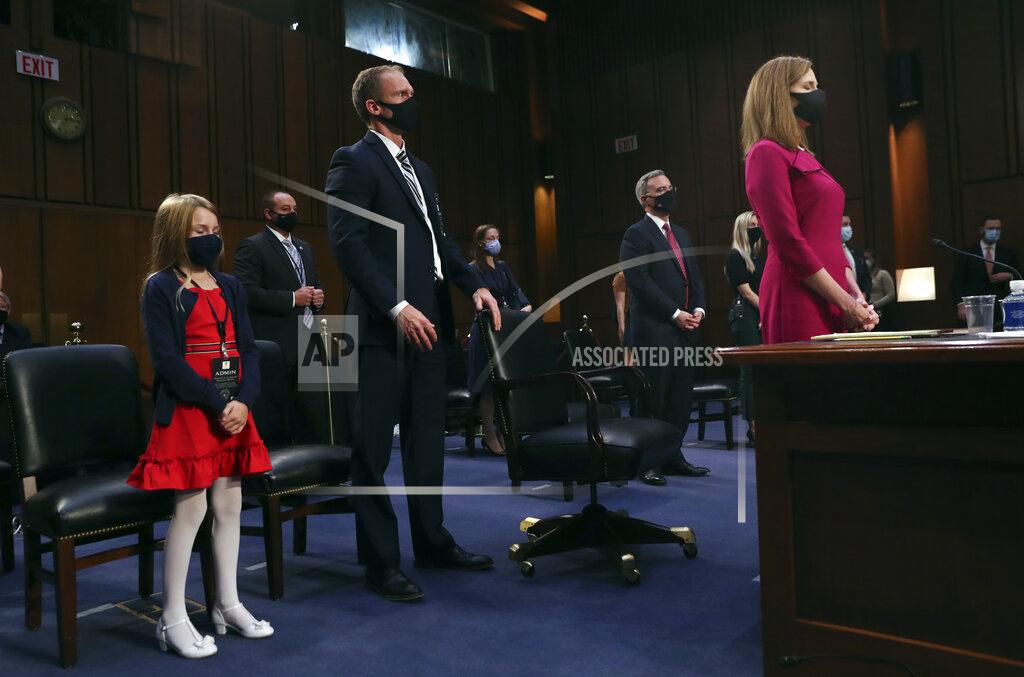 Leah Millis Supreme Court nominee Amy Coney Barrett stands at the end of the first day of her confirmation hearing before the Senate Judiciary Committee, Monday, Oct. 12, 2020, on Capitol Hill in Washington. At left is her daughter Juliet and husband Jesse and White House counsel Pat Cipollone. (Leah Millis/Pool via AP)