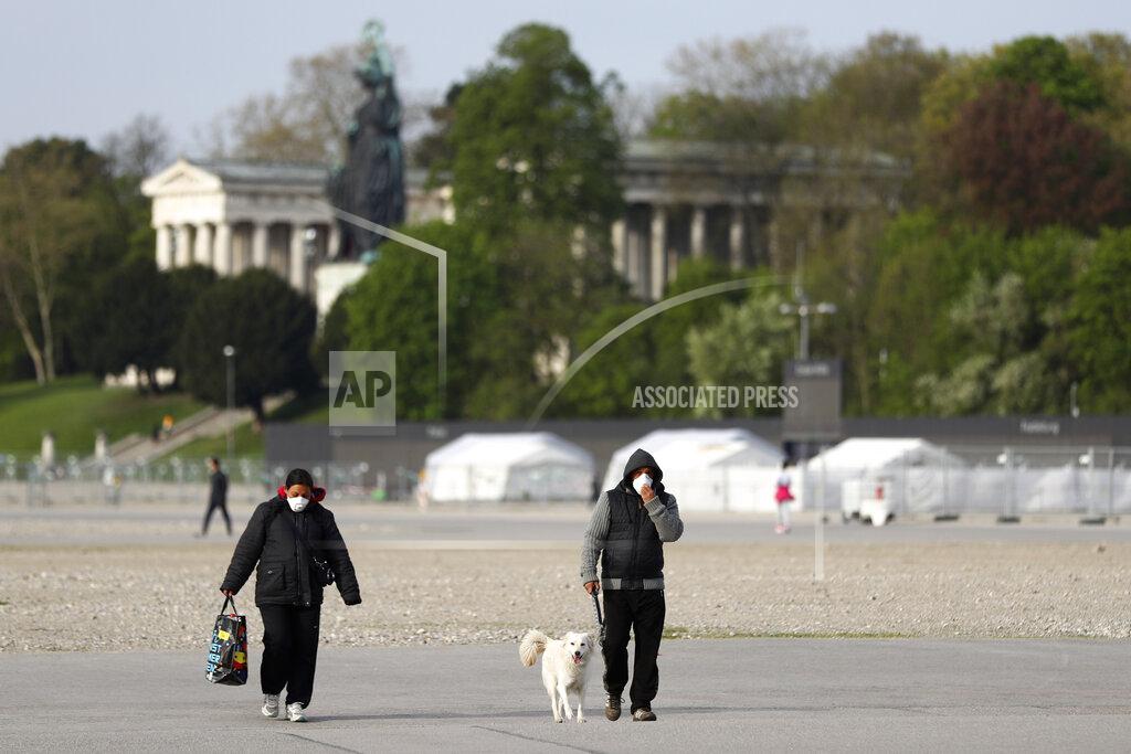 Matthias Schrader People wearing protection masks as they across the 'Theresienwiese', the Oktoberfest beer festival area, in Munich, Germany, Tuesday, April 21, 2020. Bavarian state governor Markus Soeder and Munich mayor Dieter Reiter announced at a news conference that the Oktoberfest is cancelled this year because the coronavirus outbreak. (AP Photo/Matthias Schrader)