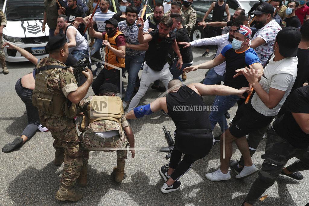 Bilal Hussein FILE - In this April 19, 2021 file photo, opponents of Judge Ghada Aoun try to strip an army soldier of his rifle as scuffles break out during a sit-in outside the Justice Palace, in Beirut, Lebanon. A public feud in recent weeks among prosecutors has starkly demonstrated how Lebanon's system of sectarian factions is paralyzing Lebanon's judicial system and snarling attempts to root out corruption. Aoun, a prominent prosecutor says she is trying to go after rampant corruption but her critics say she is only targeting enemies of her ally, the president. (AP Photo/Bilal Hussein, File)