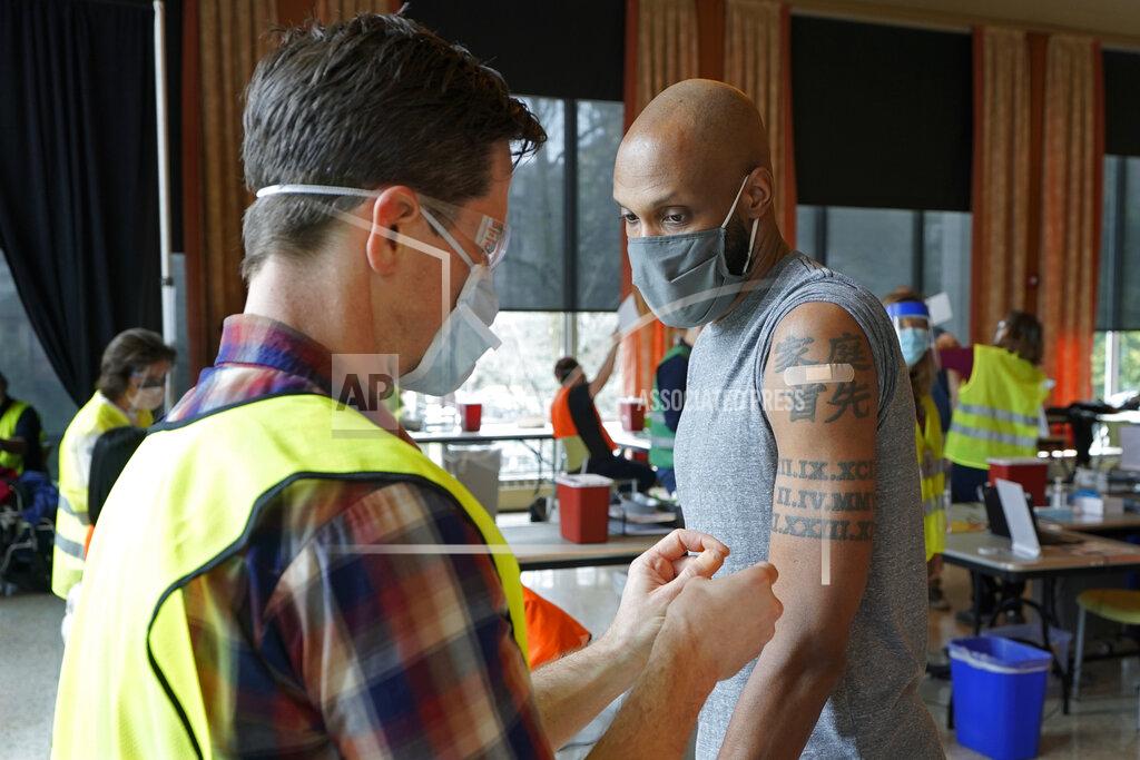 Ted S. Warren Shawn Brown, right, receives the second does of the Moderna COVID-19 vaccine from a volunteer worker at left, at a mass vaccination clinic at Seattle University, Friday, Feb. 26, 2021, in Seattle. Brown got his first dose of the vaccine in January after a broken freezer storing the vaccine led to an urgent call over social media and other channels for people to rush in and be vaccinated before the doses expired. As states ramp up vaccination distribution in the fight against the coronavirus, volunteers are needed to do everything from direct traffic to check people in to keep vaccination sites running smoothly. In return for their work, they're often given a shot — including those who are young and healthy and may not have otherwise been able to receive the shot until later in the year. (AP Photo/Ted S. Warren)