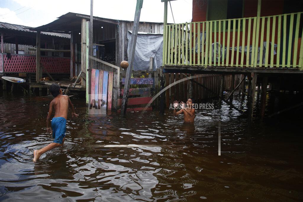 Edmar Barros Children play on a street flooded by the rise of the Negro river in Iranduba, Amazonas state, Brazil, Monday, May 23, 2022. The Amazon region is being hit hard by flooding with 35 municipalities that are facing one of their worst floods in years and the water level is expected to rise over the coming months. (AP Photo/Edmar Barros)