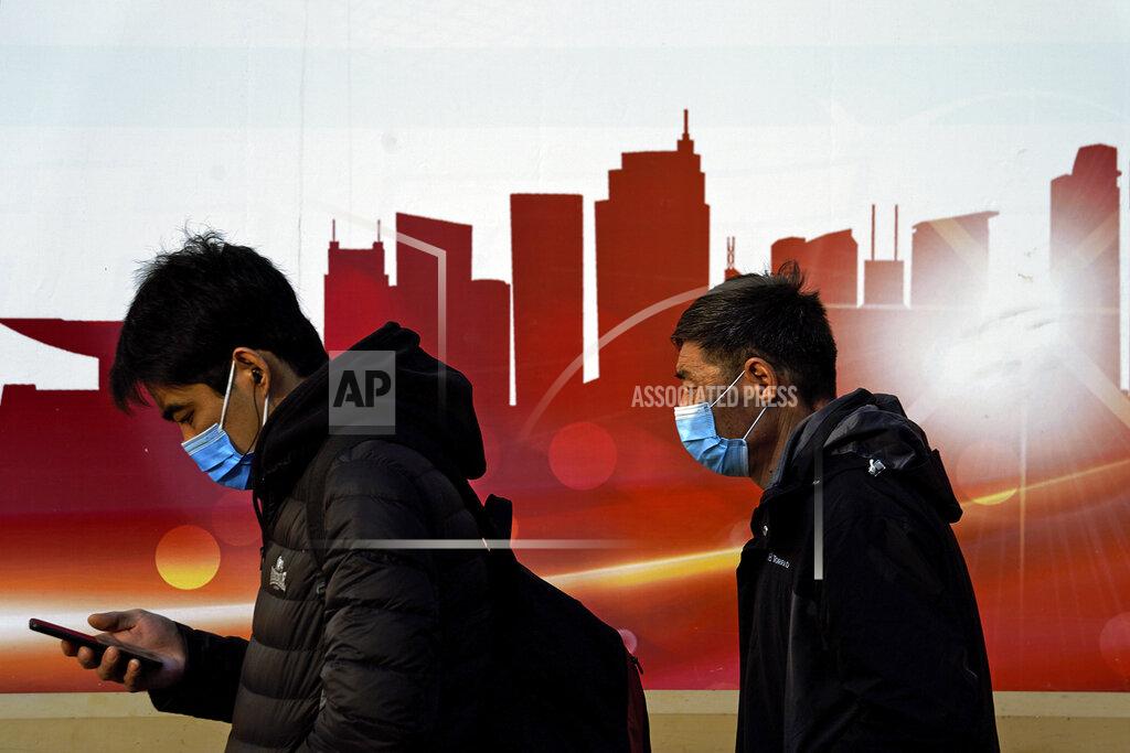 Andy Wong People wearing face masks to help curb the spread of the coronavirus walk by a moral depicting China's skyscrapers along a street in Beijing, Sunday, Dec. 6, 2020. Provincial governments across China are placing orders for experimental, domestically made coronavirus vaccines, though health officials have yet to say how well they work or how they may reach the country's 1.4 billion people. (AP Photo/Andy Wong)