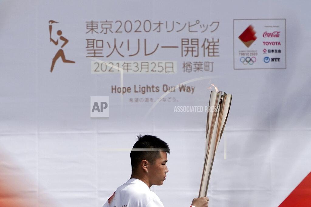 Local torchbearer Mahiro Abe, 19, carries the Olympic torch route of the first section of the Fukushima Torch Relay in Naraha, Fukushima prefecture, northeastern Japan, Thursday, March 25, 2021. The torch relay for the postponed Tokyo Olympics began its 121-day journey across Japan on Thursday and is headed toward the opening ceremony in Tokyo on July 23. (AP Photo/Eugene Hoshiko)