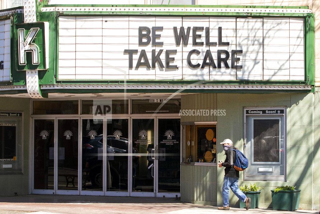 FILE - This April 13, 2020, file photo shows a pedestrian wearing a mask passing under the marquee at the Kenworthy Performing Arts Centre during the coronavirus outbreak in Moscow, Idaho. Idaho nursing homes have been hit hard by the coronavirus pandemic, with at least 150 cases reported at 16 different long-term care facilities in the state. (Geoff Crimmins/Moscow-Pullman Daily News via AP, File)