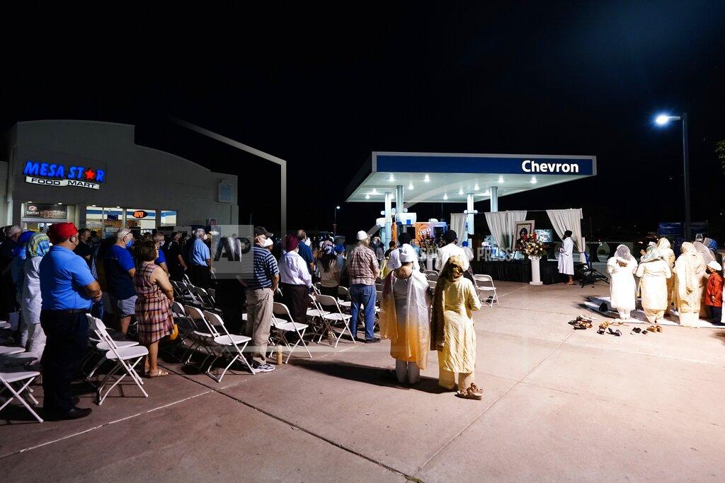Ross D. Franklin Family and friends gather for a memorial service on the 20th anniversary of the murder of Balbir Singh Sodhi, at the gas station owned by the Sodhi family, Wednesday, Sept. 15, 2021, in Mesa, Ariz. Sikh businessman Balbir Singh Sodhi was helping plant a flower bed at his Arizona gas station when he was shot dead by a man seeking to avenge 9/11. Mistaken for an Arab Muslim because of his turban and beard, Sodhi was the first person to die in a wave of bias crimes unleashed by the attacks. (AP Photo/Ross D. Franklin)
