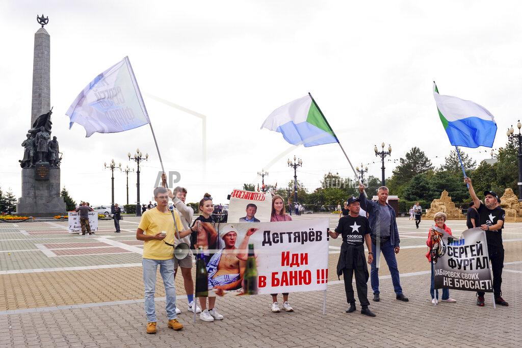 Sergei Demidov A small group of demonstrators hold posters reading "Degtyaryov, go to the bathhouse!!!" and "I'm, we are Sergei Furgal" in Khabarovsk, Russia, in the country's Far East, on Saturday, Sept. 11, 2021. A few demonstrators each evening gather in a persistent reminder of the mass protests last year demanding the release of Furgal, the region's former governor, who was replaced by the Kremlin with Mikhail Degtyaryov. (AP Photo/Sergei Demidov)
