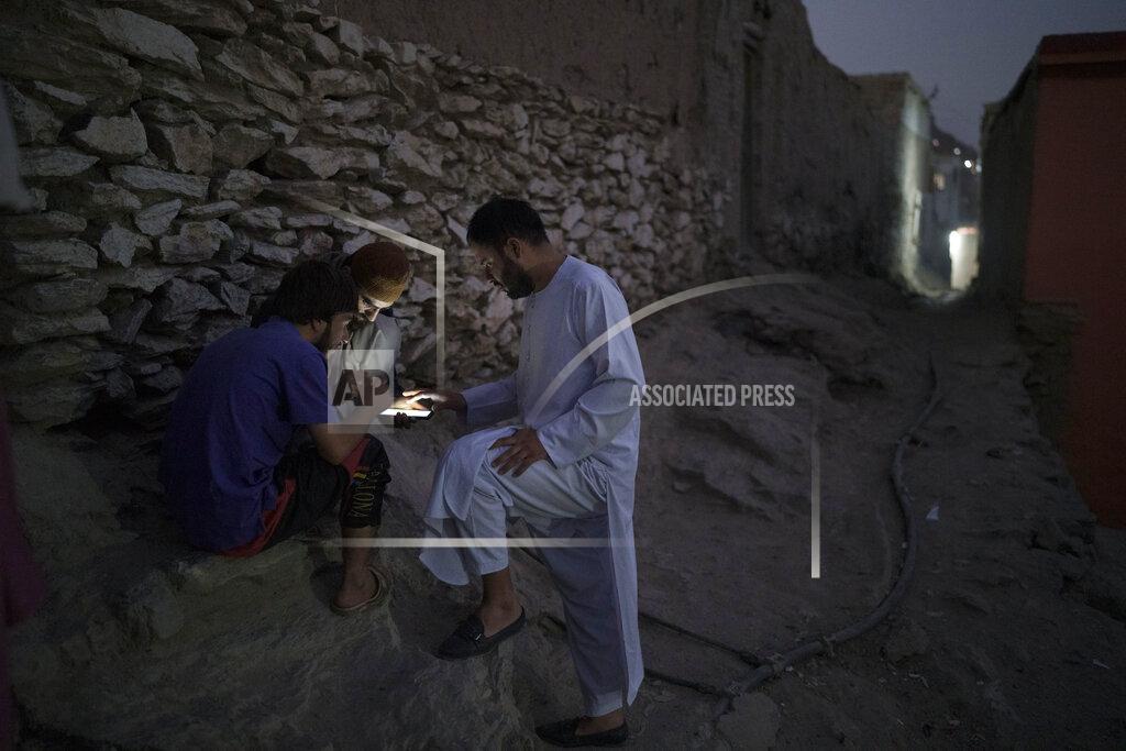 Felipe Dana Afghans play games on a cellphone outside their home in Kabul, Afghanistan, Saturday, Sept. 11, 2021. (AP Photo/Felipe Dana)