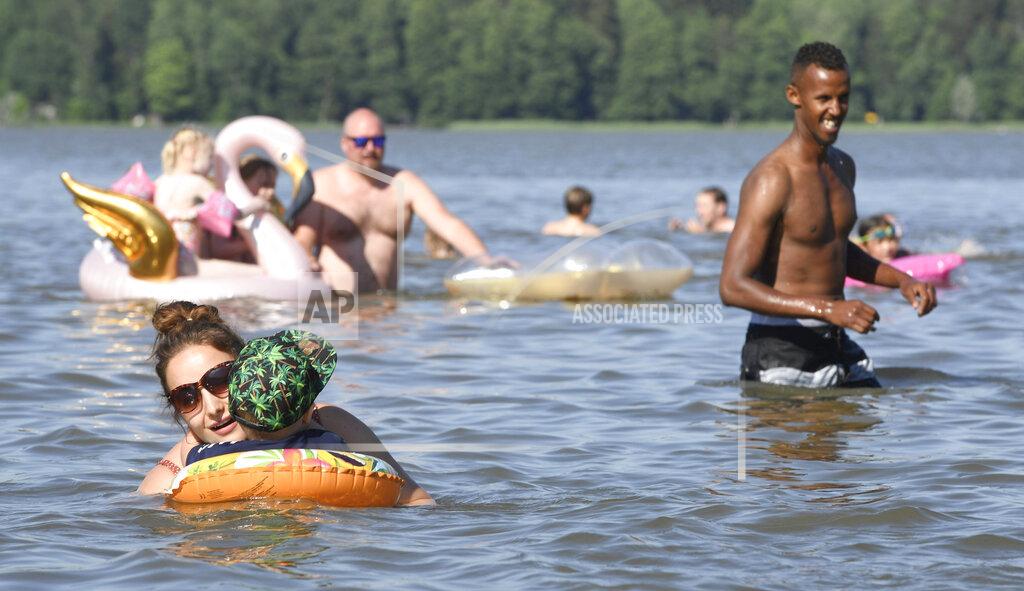 People enjoy hot summer day in a lake in Espoo, Finland, on June 26, 2020. In a year of untimely deaths from the coronavirus, economic decline and social loneliness, The World Happiness Report revealing the world’s happiest countries shows Friday March 19, 2021, Nordic countries topped the index, with Finland leading for the fourth consecutive year. (Heikki Saukkomaa/Lehtikuva via AP)