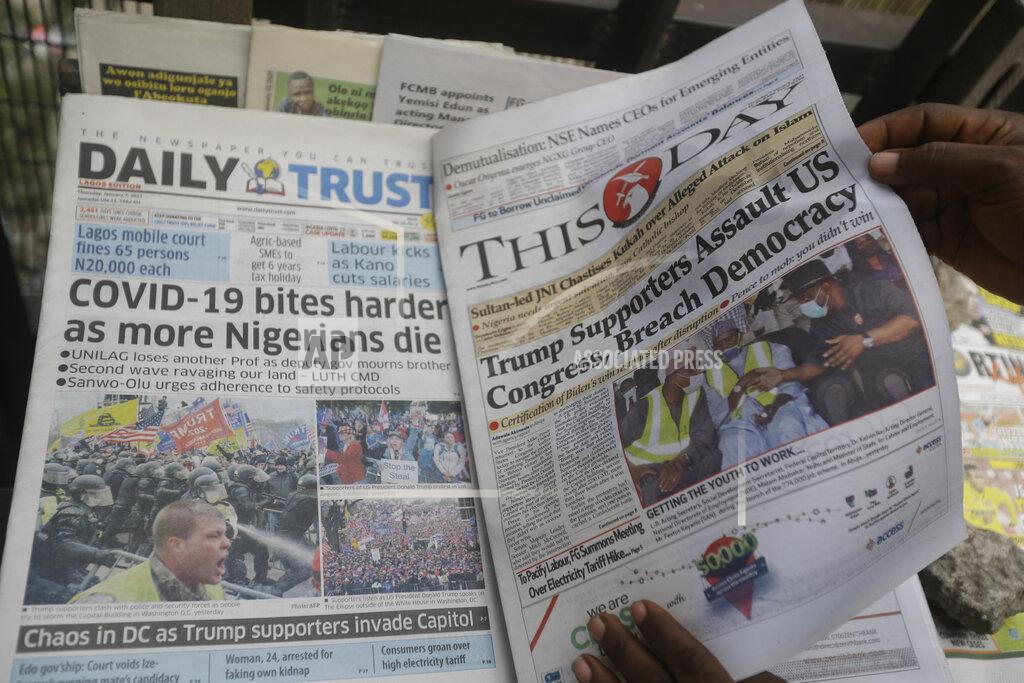 Sunday Alamba A man reads a newspaper reacting to the news of the assault on U.S Congress, in Lagos, Nigeria, Thursday Jan. 7, 2021. New reports showing Police with gun drawn as protesters try to break into the House Chamber at the U.S. Capitol on Wednesday, in Washington, USA.(AP Photo/ Sunday Alamba)