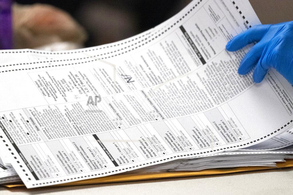 FILE - In this April 8, 2020, file photo, a City of Milwaukee Election Commission worker processes absentee ballots for the state's primary election, in downtown Milwaukee, Wis. A conservative law firm asked the Wisconsin Elections Commission on Monday, June 8 to outlaw ballot harvesting in the state, the process by which outside groups, typically partisan, help to send or return large numbers of absentee ballots. (Mark Hoffman/Milwaukee Journal-Sentinel via AP, File)