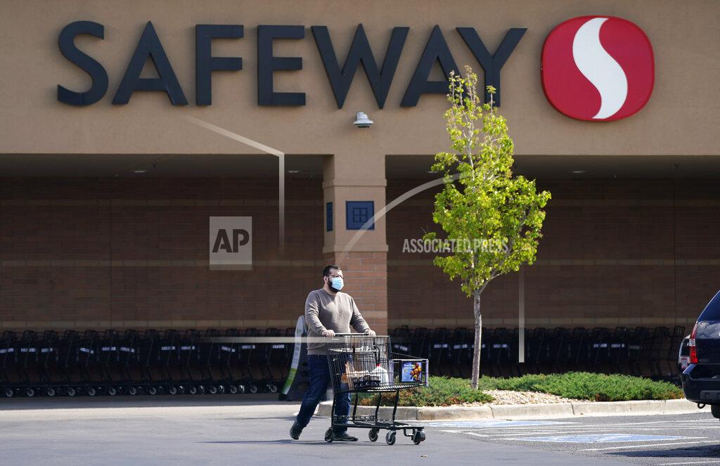 David Zalubowski In this Wednesday, May 19, 2021, photograph, a shopper wearing a face covering uses a cart to wheel his purchases to a vehicle at a Safeway grocery store in Aurora, Colo. Many workers in retail sales jobs who are fully vaccinated are now concerned about risks posed as retailers change their mask-wearing policies for customers. (AP Photo/David Zalubowski)