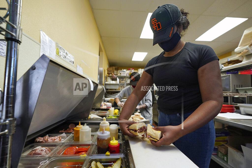 Rich Pedroncelli Lakshmi Davulur prepares a sandwich for a lunch patron at the San Francisco Deli in Redding, Calif., Thursday, Dec. 3, 2020. Brenda Luntey, who owns the deli with her husband, is openly violating the state's order to close her restaurant to indoor dining. She takes all the precautions advised, but doesn't force customers to wear a face mask. "I want people to understand we are not thumbing our nose at the government,"said Luntey, "I'm trying to keep my business alive." (AP Photo/Rich Pedroncelli)
