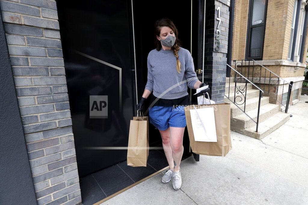 Nam Y. Huh Marry Hammell, an Alinea restaurant staffer, carries out orders for a customer in Chicago, Saturday, June 20, 2020. Some of the world's best restaurants have had to make a quick pivot to weather the coronavirus. Alinea used to offer an 18-course tasting menu for $365; now it's making carryout meals for $49.94 (AP Photo/Nam Y. Huh)
