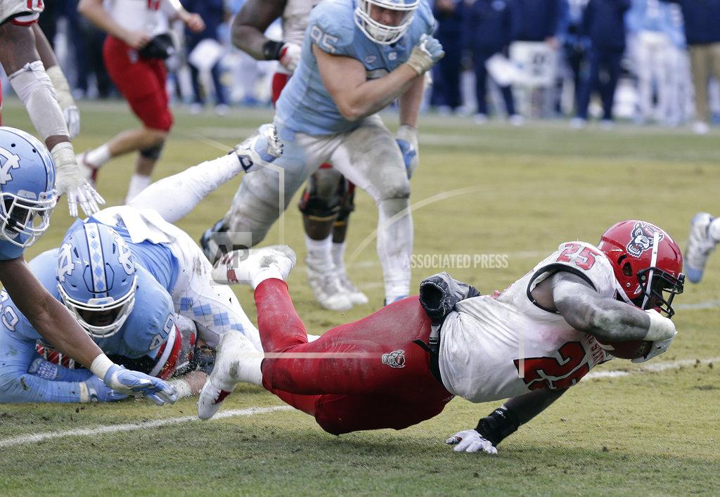Gerry Broome North Carolina State's Reggie Gallaspy II (25) struggles for extra yardage as North Carolina's Dominique Ross, left, and Jeremiah Clarke (49) attempt to tackle during overtime in an NCAA college football game in Chapel Hill, N.C., Saturday, Nov. 24, 2018. North Carolina State won 43-28. (AP Photo/Gerry Broome)