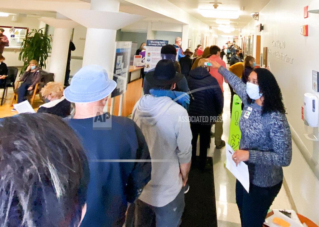 Jethro Bowers In this photo provided by The Mendocino Voice, a health care worker directs people lined up in the Adventist Health Ukiah Valley Medical Center, Monday, Jan. 4, 2021, in Ukiah, Calif., to get the Moderna COVID-19 vaccination during an emergency vaccine drive. A power failure for the freezer holding the county's ration of the Moderna vaccines forced the emergency distribution of 850 doses of that vaccine. (Jethro Bowers/The Mendocino Voice via AP)