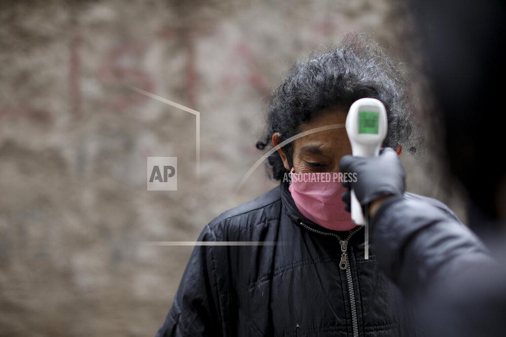 Natacha Pisarenko A volunteer measures the temperature of a resident inside the Fraga slum during a government-ordered lockdown to curb the spread of the new coronavirus, in Buenos Aires, Argentina, Saturday, June 6, 2020. (AP Photo/Natacha Pisarenko)