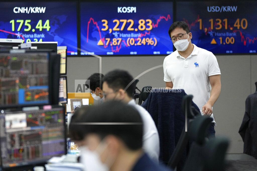 Ahn Young-Joon A currency trader passes by screens showing the Korea Composite Stock Price Index (KOSPI), center, and the foreign exchange rate between U.S. dollar and South Korean won, right, at the foreign exchange dealing room of the KEB Hana Bank headquarters in Seoul, South Korea, Friday, June 18, 2021. Asian shares mostly rose Friday, as investors digested the latest message from the U.S. Federal Reserve on raising short-term interest rates by late 2023. (AP Photo/Ahn Young-joon)