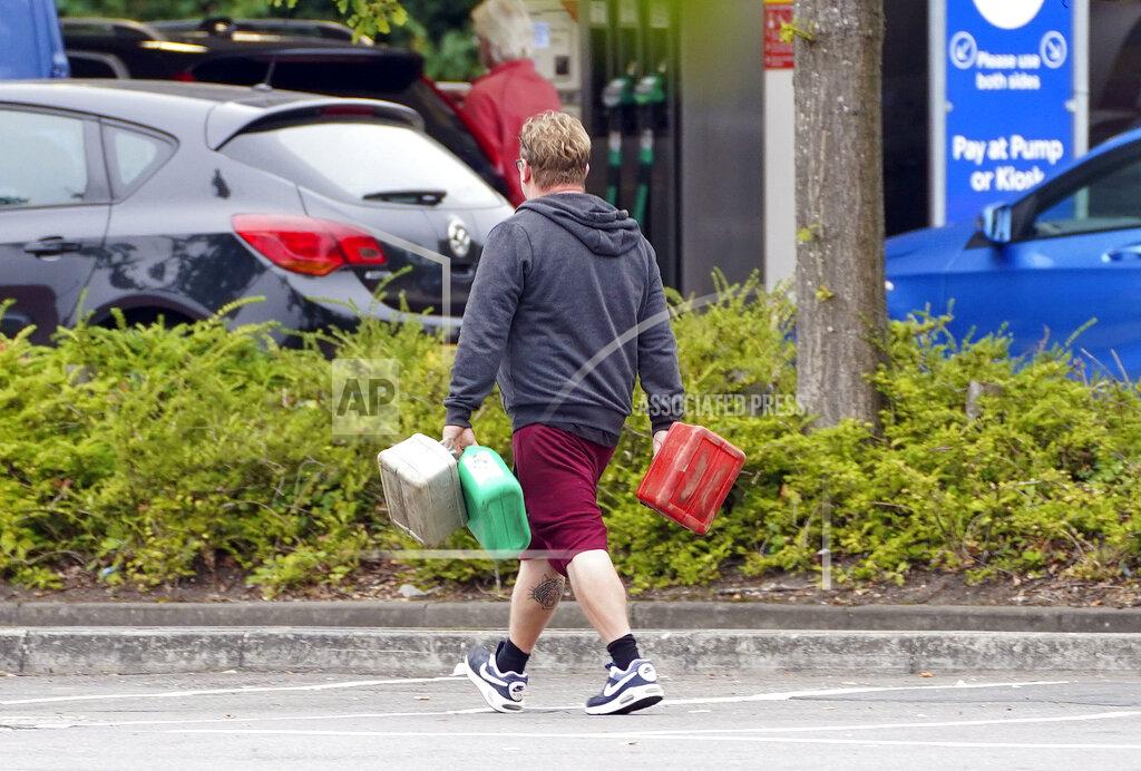 Steve Parsons A man carries containers to a petrol station in Bracknell, England, Saturday Sept. 25, 2021. The haulage industry says the U.K. is short tens of thousands of truckers, due to a perfect storm of factors including the coronavirus pandemic, an aging workforce and an exodus of European Union workers following Britain’s departure from the bloc. BP and Esso shut a handful of their gas stations this week, and motorists have formed long lines as they try to fill up in case of further disruption. (Steve Parsons/PA via AP)
