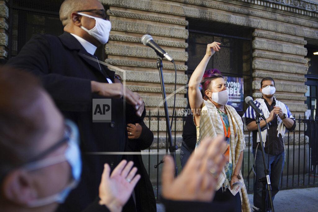 Emily Leshner Shira Kline, a director of worship for Lab/Shul, a Jewish community-based organization, leads a group in song during an interfaith gathering outside of the Judson Memorial Church near Washington Square Park in New York, Wednesday, Nov. 4, 2020. Muslims, Jews, Christians and Buddhists came together to show solidarity among faith communities as the country awaits the final result of the U.S. presidential election. (AP Photo/Emily Leshner)