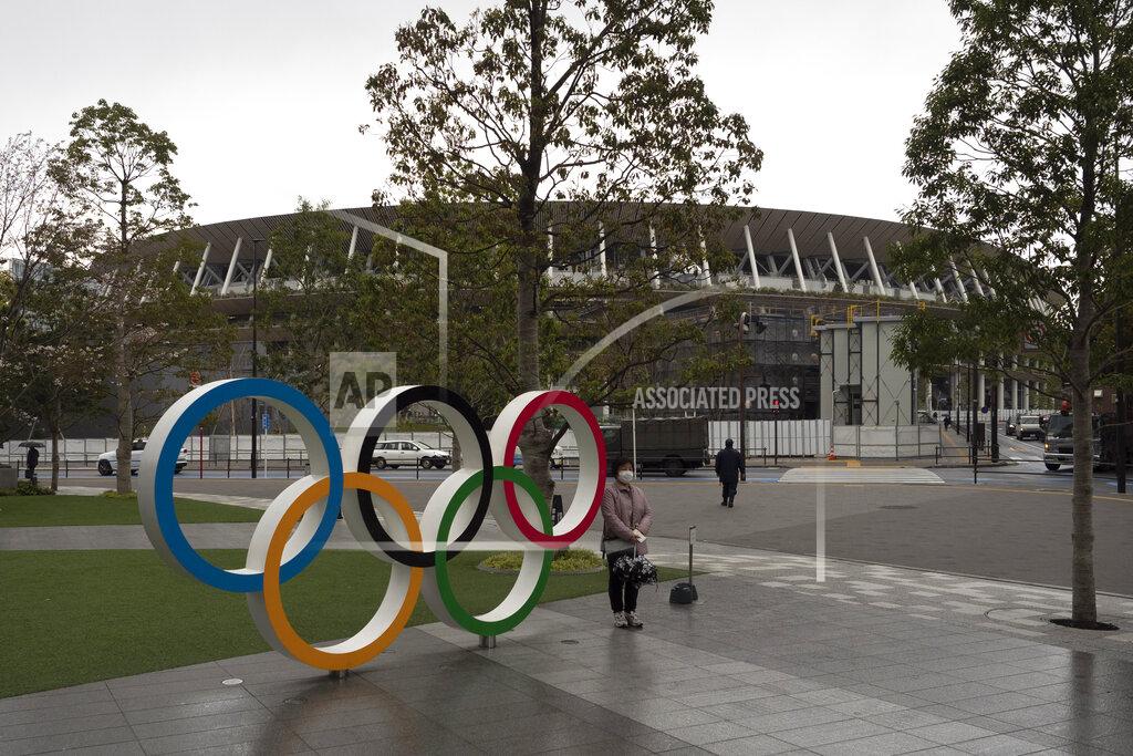 Jae C. Hong A woman pauses for photos next to the Olympic rings near the New National Stadium in Tokyo, Monday, March 23, 2020. The IOC will take up to four weeks to consider postponing the Tokyo Olympics amid mounting criticism of its handling of the coronavirus crisis that now includes a call for delay from the leader of track and field, the biggest sport at the games. (AP Photo/Jae C. Hong)