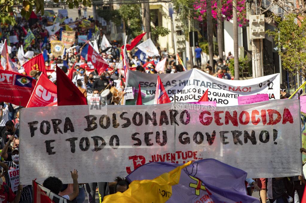 Andre Penner Demonstrators march holding a banner with a message that reads in Portuguese; "Get out genocidal Bolsonaro and all your government" during a protest against Brazilian President Jair Bolsonaro and his handling of the pandemic and economic policies protesters say harm the interests of the poor and working class, in Cuiaba, Brazil, Saturday, June 19, 2021. (AP Photo/Andre Penner)
