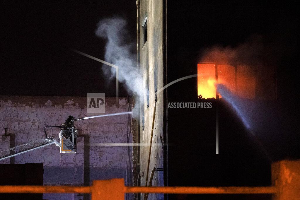 Joan Mateu Firefighters work to extinguish a fire at a building in Badalona, Barcelona, Spain, Thursday, Dec. 10, 2020. Authorities in northeastern Spain say a fire has raged through an abandoned building occupied by squatters in the city of Badalona, injuring at least 17 people, including two in critical condition. Firefighters say they rescued around 30 people from windows as the building burned late Wednesday. (AP Photo/Joan Mateu)