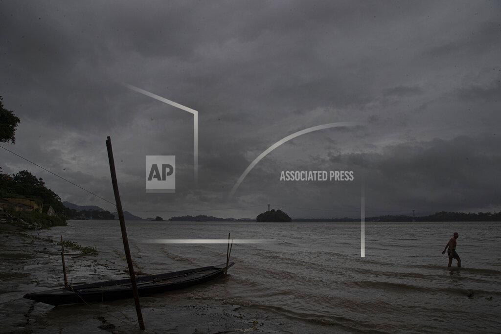 Anupam Nath An Indian fisherman walks in the middle of heavy wind and rain in the river Brahmaputra in Gauhati, India, Thursday, May 21, 2020. A powerful cyclone ripped through densely populated coastal India and Bangladesh, blowing off roofs and whipping up waves that swallowed embankments and bridges and left entire villages without access to fresh water, electricity and communications. (AP Photo/Anupam Nath)