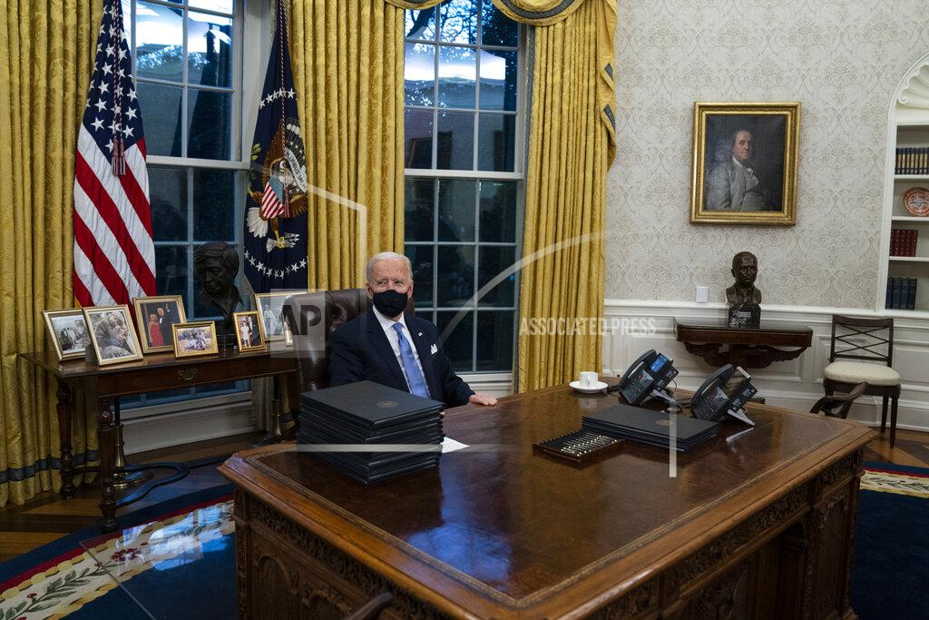 Evan Vucci President Joe Biden signs a series of executive orders in the Oval Office of the White House, Wednesday, Jan. 20, 2021, in Washington. (AP Photo/Evan Vucci)