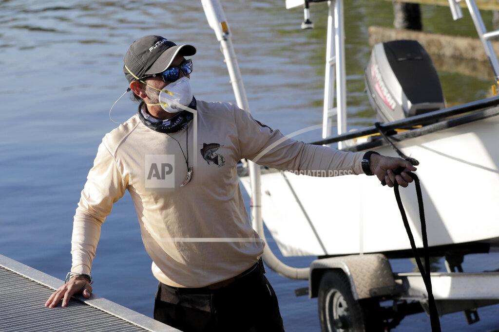 Lynne Sladky Manuel Figueroa wears a protective face mask as he puts his boat into the water at the Flamingo boat ramp during the new coronavirus pandemic, Monday, May 4, 2020, in Everglades National Park in Florida, as the park gradually reopens to the public in phases. The park closed to the public after Miami-Dade County ordered closures of public parks and beaches in an effort to slow the spread of COVID-19. (AP Photo/Lynne Sladky)