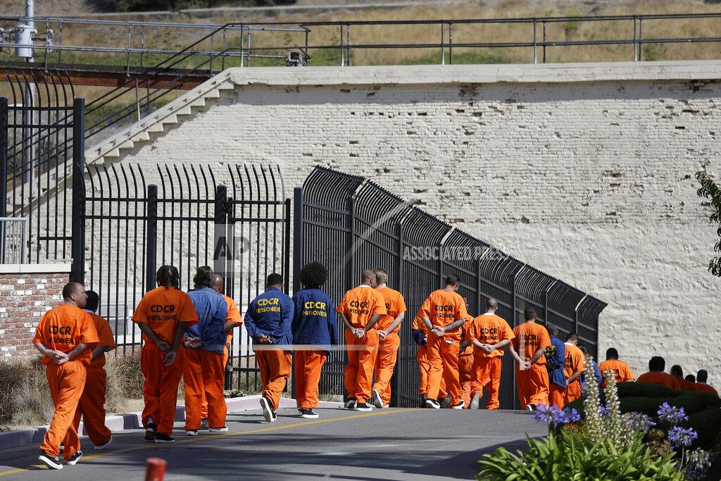 Eric Risberg FILE - In this Aug. 16, 2016, file photo, general population inmates walk in a line at San Quentin State Prison in San Quentin, Calif. A California appeals court has ordered state corrections officials to cut the population of one of the world's most famous prisons to less than half of its designed capacity, citing officials' "deliberate indifference" to the plight of inmates during the coronavirus pandemic. State prison officials said Wednesday, Oct. 21, 2020, that they are deciding whether to appeal the order, which otherwise will force them to parole or transfer about 1,100 inmates serving time in San Quentin State Prison north of San Francisco. (AP Photo/Eric Risberg, File)