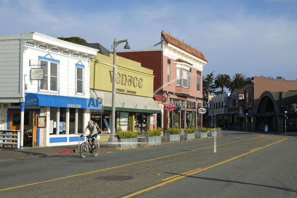 FILE - In this March 17, 2020 file photo a bicyclist rides past closed restaurants and shops in Sausalito, Calif. Restaurant owners and executives across the country fear they’ll have to repay thousands of dollars in potentially forgivable loans from the Paycheck Protection Program because rules written by the Small Business Administration are out of sync with the reality these businesses face _ many are still shut down by state and local government orders, and those that have reopened have drastically reduced revenue. (AP Photo/Eric Risberg)