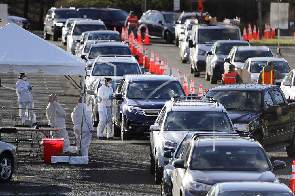 Seth Wenig FILE - In this March 24, 2020, file photo, staff at a drive-thru COVID-19 testing site talk to people waiting in line in their cars at the PNC Bank Arts Center in Holmdel, N.J. (AP Photo/Seth Wenig, File)