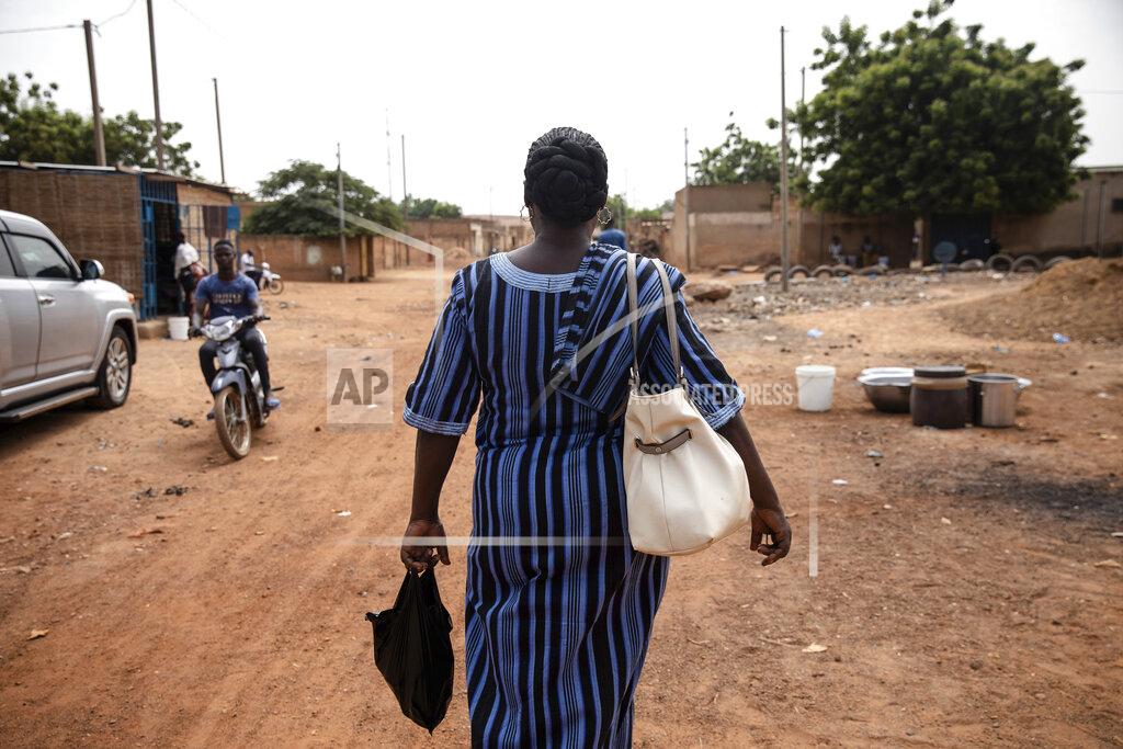 Sophie Garcia Mariama Sawadogo, 44, who works as a radio host at Zama Radio in Kaya, Burkina Faso, walks back home Monday, Oct. 25, 2021. Many guests and listeners in Burkina Faso call her "aunty" as she gently guides them to the right answers and awards prizes such as soap and washing buckets. In the West African country of Burkina Faso, many feel the government has let them down during the pandemic. Tests, vaccines and messaging often miss many residents, despite a $200 million budget for virus-response efforts. In a region where women are responsible for family work and community relationships, they’ve stepped up to fill in gaps. (AP Photo/Sophie Garcia)