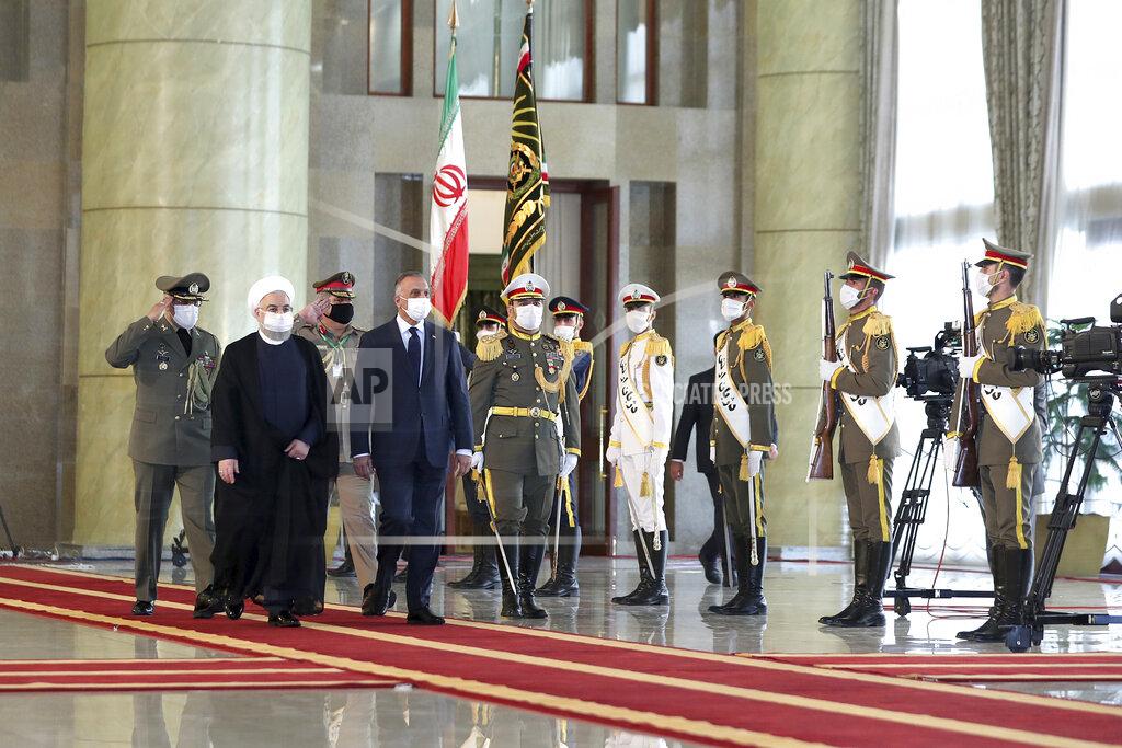 Uncredited In this photo released by the official website of the office of the Iranian Presidency, Iraqi Prime Minister Mustafa al-Kadhimi, fourth left, reviews an honor guard as he is welcomed by President Hassan Rouhani, second left, as they all wear protective face masks to help prevent spread of the coronavirus, during an official arrival ceremony, in Tehran, Iran, Tuesday, July 21, 2020. (Iranian Presidency Office via AP)