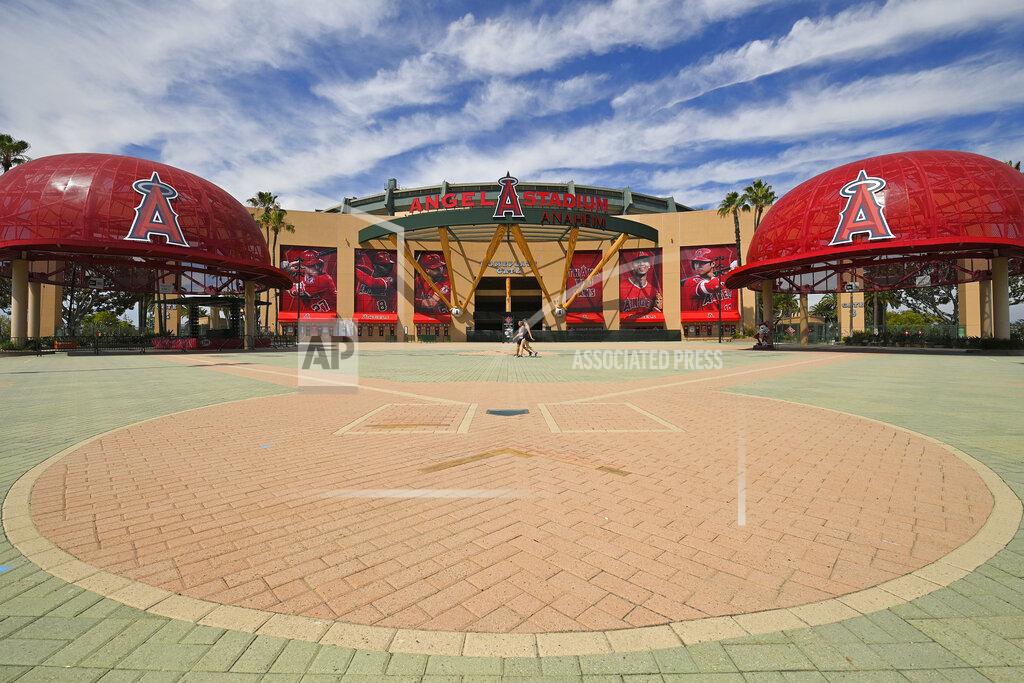 Mark J. Terrill People walk by the front of Angel Stadium, Thursday, June 25, 2020, in Anaheim, Calif. By the time Major League Baseball returns in late July, it will have been more than four months since teams last played. The season is now going to be a 60-game sprint to the finish, held in ballparks without fans and featuring some unusual rules. (AP Photo/Mark J. Terrill)
