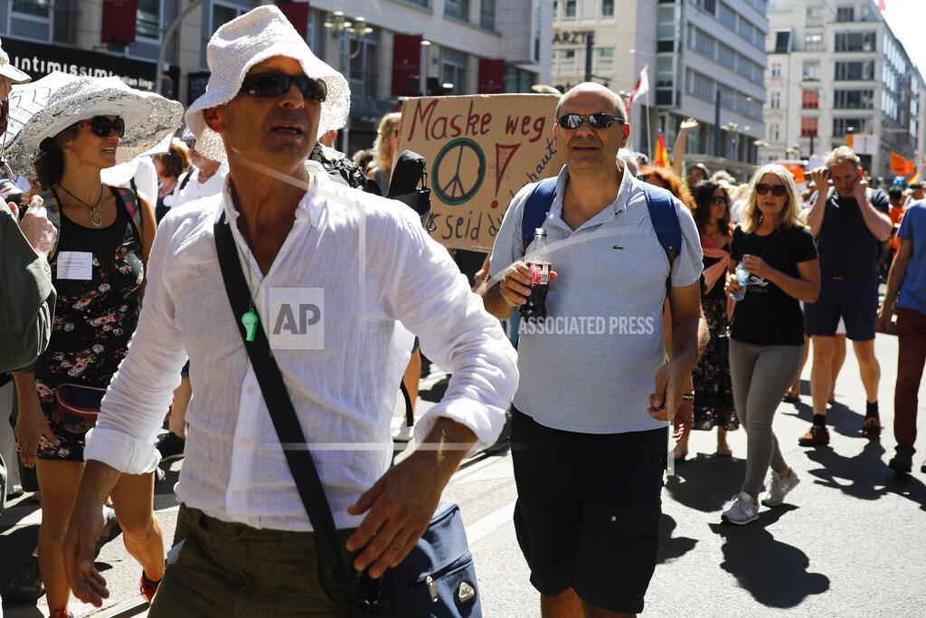 Markus Schreiber Protestors show a poster reading: 'Mask away' as they attend a demonstration with the slogan ‚The end of the pandemic - freedom day' - against coronavirus restrictions in Berlin, Germany, Saturday, Aug. 1, 2020. It comes amid increasing concern about an upturn in infections in Germany. (AP Photo/Markus Schreiber)