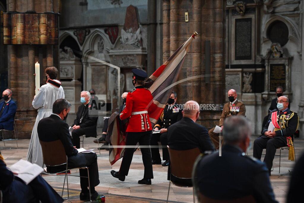 Jeremy Selwyn The Padre’s flag, the British Union flag that was used by the Reverend David Railton as an altar cloth on the battlefields of northern France during World War I, is carried through Westminster Abbey to be laid on the altar by Guardsman Rhian Morgan of the 1st Battalion Welsh Guards, watched by honoured guests attending the Armistice Day service at Westminster Abbey in London, Wednesday, Nov. 11, 2020. The specially arranged service, with social distancing because of the coronavirus, commemorates the 102nd anniversary of the armistice ending World War I, and one hundred years since the symbolic interment of the Unknown Warrior at Westminster Abbey. David Railton used the flag as an altar cloth during the War in Ypres, when he first thought of the idea of the unknown warrior. (Jeremy Selwyn/Pool via AP)