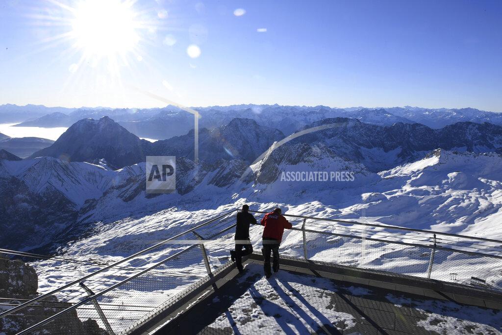 Angelika Warmuth Two employees look out over the closed ski resort at the Zugspitze in Grainau, Germany, Monday, Nov 30, 2020. The skiing areas are prepared but due to the Corona pandemic restrictions skiing is not allowed at the area. (Angelika Warmuth/dpa via AP)