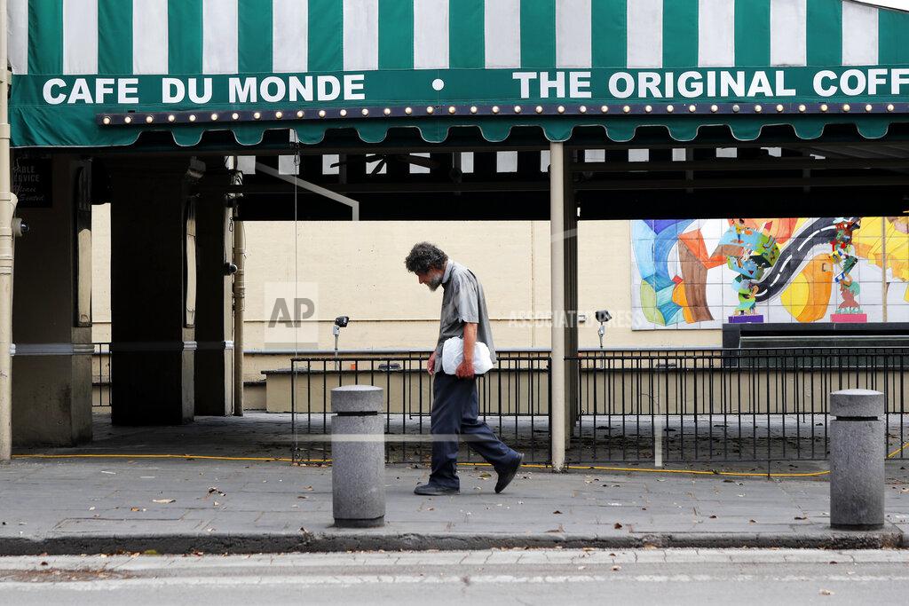 Gerald Herbert FILE - In this March 27, 2020 file photo, a man walks past a closed Cafe Du Monde, in the French Quarter of New Orleans, normally bustling with tourists, but now nearly completely deserted due to the new coronavirus pandemic. Where political divides marred early recovery efforts after Hurricane Katrina in 2005, Louisiana is showing rare political unity in the fight against the new coronavirus. (AP Photo/Gerald Herbert, File)