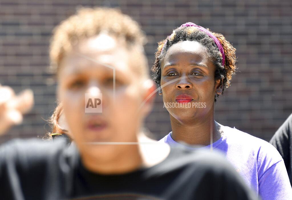 Thomas Peipert Community activist Shenika Carter, background, listens to Candice Bailey speak during a news conference in Aurora, Colo., on Wednesday, July 28, 2021. Local activists and former members of Aurora's community police task force gathered to call attention to police brutality. Aurora police announced Monday that an officer was arrested after video showed him using his pistol to beat a man he was trying to take into custody, choking him and threatening to kill him, while another officer was accused of failing to stop her colleague. (AP Photo/Thomas Peipert)