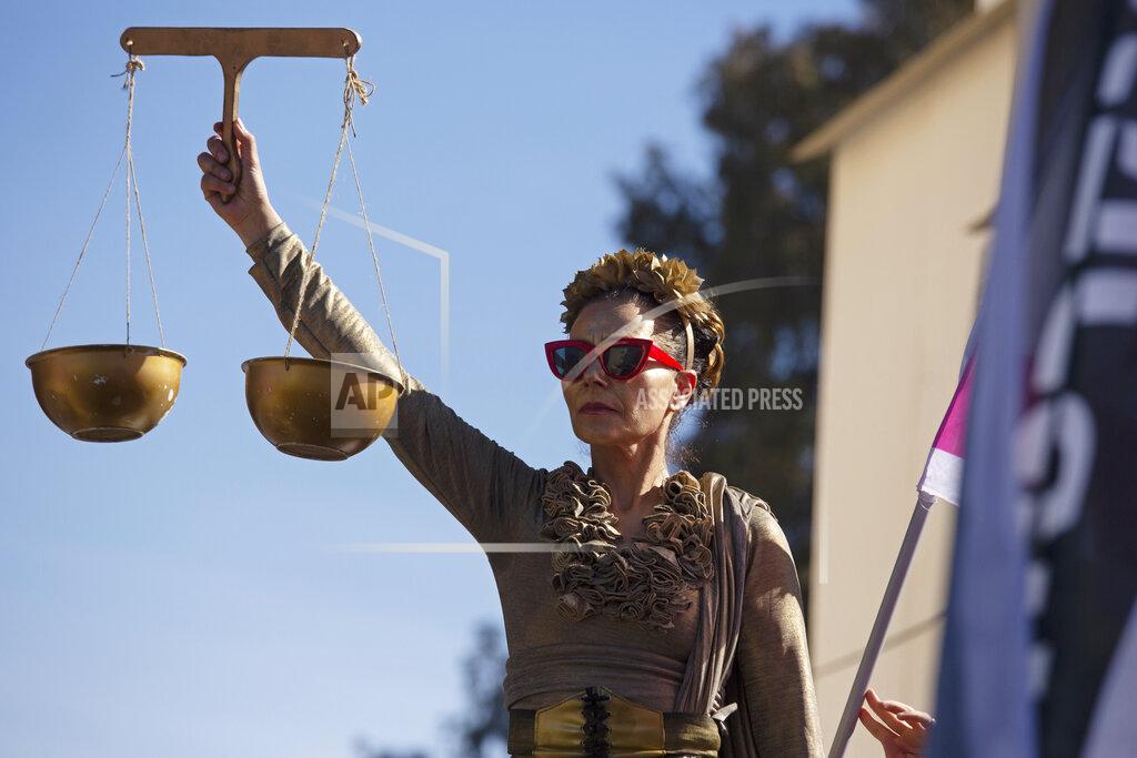 Maya Alleruzzo A protester holds the scales of justice outside the District Court during a hearing in Israeli Prime Minister Benjamin Netanyahu's corruption trial, in Jerusalem, Monday, Feb. 8, 2021. Netanyahu has pleaded not guilty as his trial on corruption charges resumes in a Jerusalem courtroom just weeks before national elections in which he hopes to extend his 12-year rule. (AP Photo/Maya Alleruzzo)