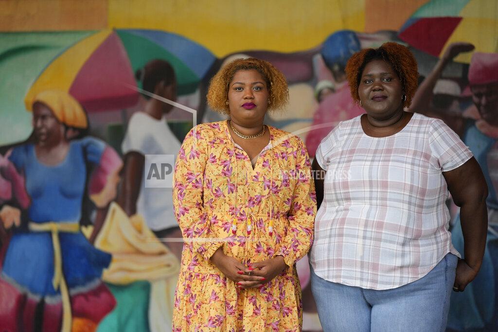 Rebecca Blackwell Krystina Francois, left, and Francesca Menes, children of Haitian immigrants to the U.S. and co-founders of the Black Collective, pose for a picture in front of a mural at the Little Haiti Cultural Center, Tuesday, Sept. 21, 2021, in Miami. Menes and Francois, whose advocacy organization focuses on the political needs and economic empowerment of Black people across the African diaspora, have called for the Biden administration to immediately suspend plans to remove migrants via planes bound for Haiti. (AP Photo/Rebecca Blackwell)