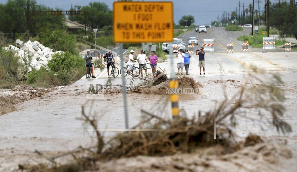 Kelly Presnell The flooded Pantano Wash in Tucson, Ariz., draws crowds of onlookers where it forced closure of Harrison Road following a night of intense storms and heavy rain, Friday, July 23, 2021. (Kelly Presnell/Arizona Daily Star via AP)
