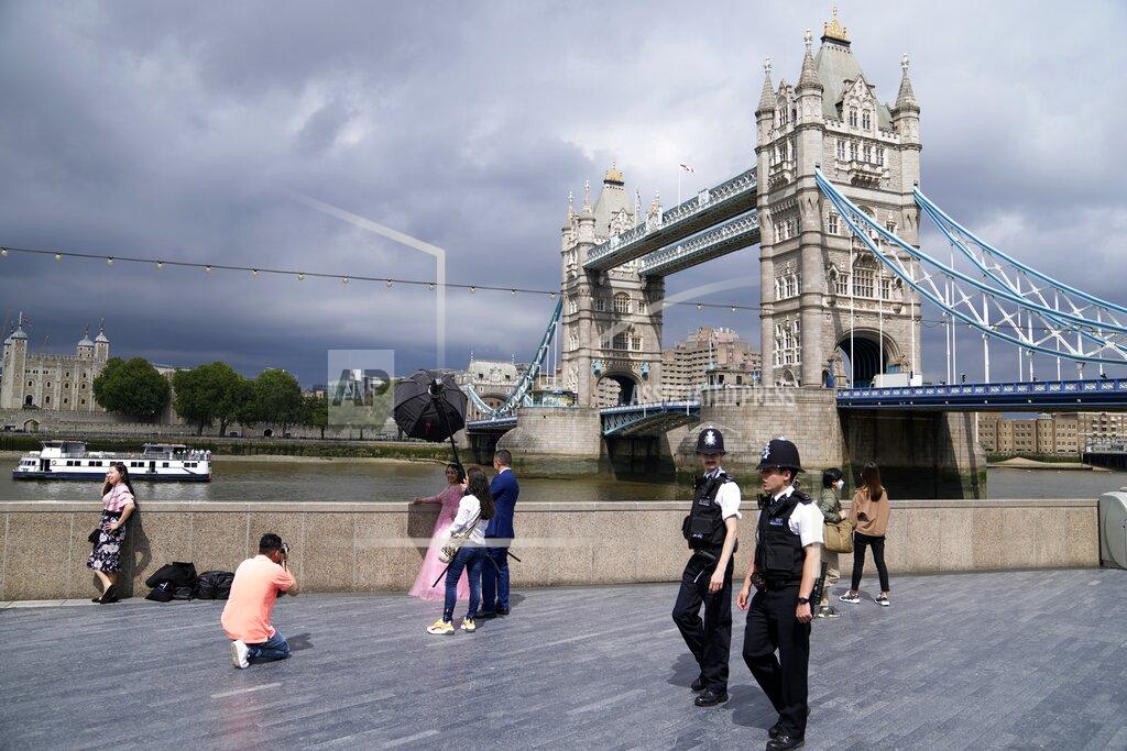 Thanassis Stavrakis FILE - In this July 3, 2021, file photo, policemen patrol near Tower Bridge as a bride is photographed on the bank of Thames river in London. Britain's Conservative government is hoping a combination of relatively high vaccination rates and common-sense behavior will keep a lid on coronavirus infections this fall and winter and avoid the need for restrictive measures. (AP Photo/Thanassis Stavrakis, File)