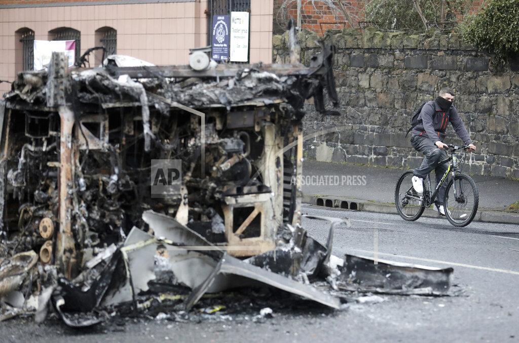 Peter Morrison A cyclist passes the remains of a burnt out bus on the Shankill road in West Belfast, Northern Ireland, Thursday, April 8, 2021. It follows another night of violence in Loyalist areas that has now spread to interface areas of the peace divide. (AP Photo/Peter Morrison)