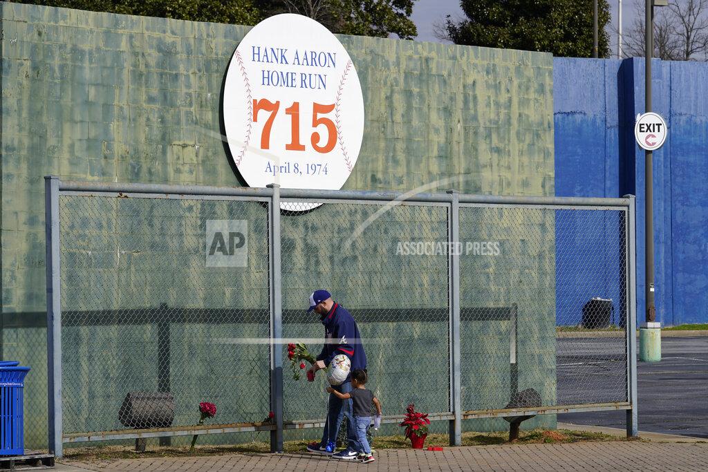 John Bazemore Les Motes and his two-year-old daughter Mahalia leave flowers, Friday, Jan. 22, 2021, in Atlanta, near the spot where a ball hit for a home run by Atlanta Braves' Hank Aaron cleared the wall to break Babe Ruth's career home run record in 1974. Aaron, who endured racist threats with stoic dignity during his pursuit of Babe Ruth but went on to break the career home run record in the pre-steroids era, died peacefully in his sleep early Friday. He was 86. (AP Photo/John Bazemore)