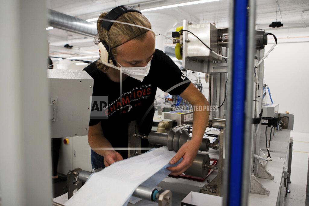 Gerardo Villalobos In this undated photo provided by Outdoor Research in September 2020, a worker adjusts material on a machine that makes surgical masks in Seattle. As the city became a major coronavirus hotspot, the clothing and sportswear company also switched gears. (Gerardo Villalobos/Outdoor Research via AP)