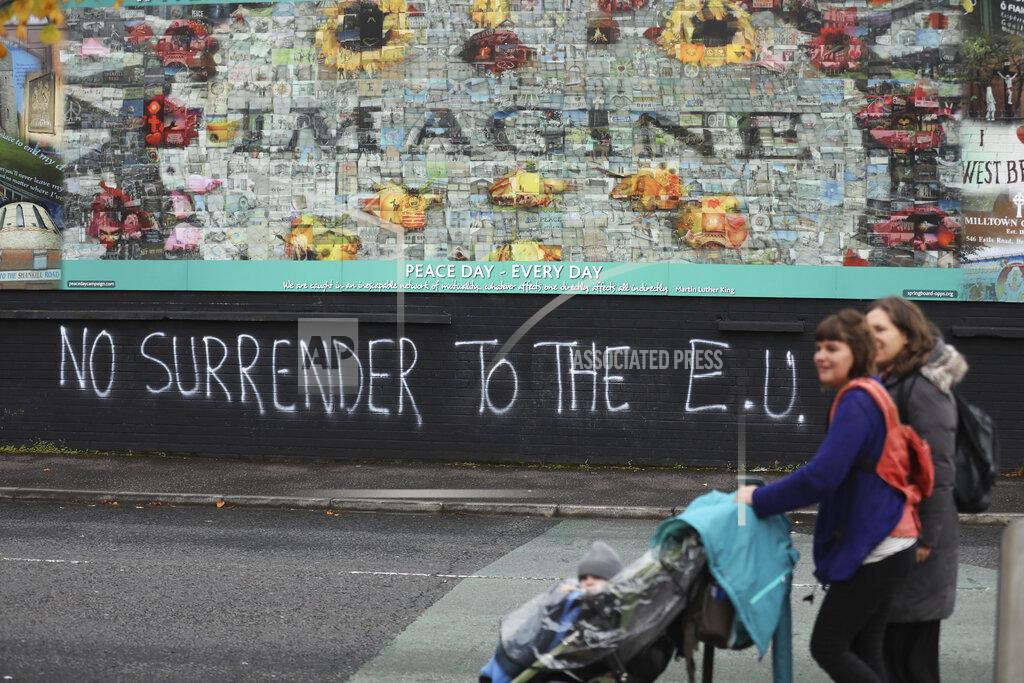 Peter Morrison FILE - In this Monday Oct. 14, 2019 file photo people walk past pro-Brexit graffiti in West Belfast Northern Ireland. The chaotic scenes during a week of violence on the streets of Northern Ireland have stirred memories of decades of Catholic-Protestant conflict, known as "The Troubles." A 1998 peace deal ended large-scale violence but did not resolve Northern Ireland's deep-rooted tensions. (AP Photo/Peter Morrison, File)