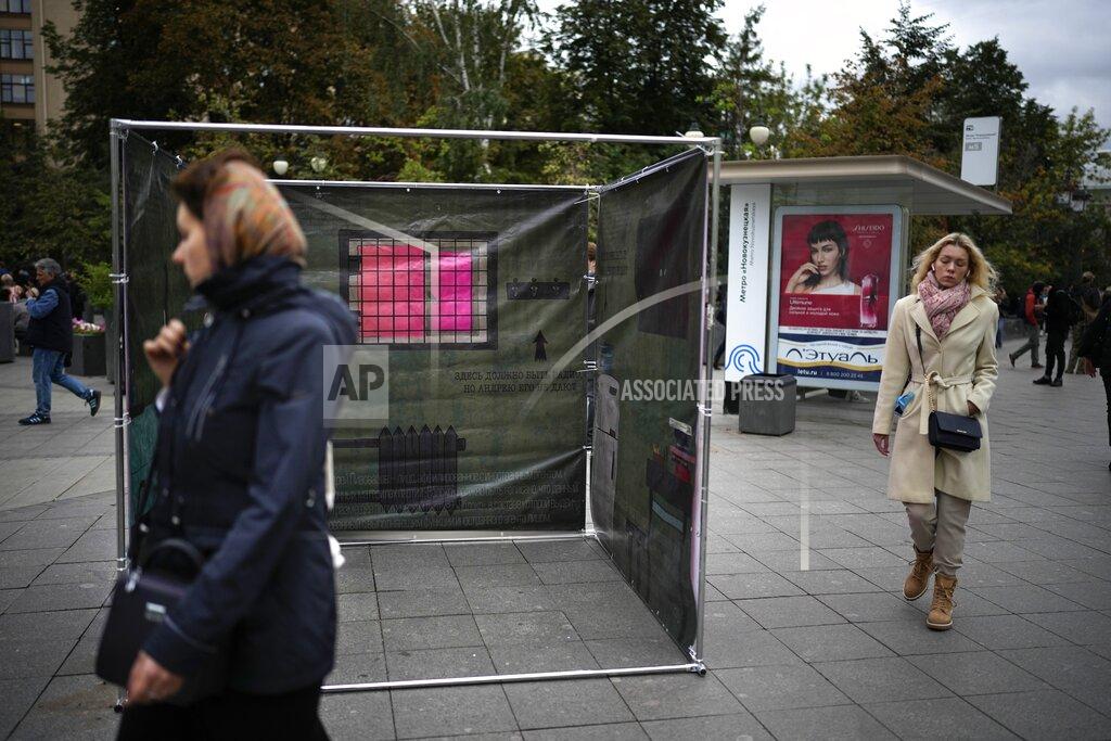 Alexander Zemlianichenko People walk past a campaign stand in Moscow, Russia, Tuesday, Sept. 7, 2021, for Andrei Pivovarov, an opposition activist who was jailed earlier this year but is allowed to run in the upcoming election for the State Duma, the lower house of the Russian parliament. Russia is holding three days of voting, ending Sunday, Sept. 19, 2021, for a new parliament that is unlikely to change the country’s political complexion. (AP Photo/Alexander Zemlianichenko)