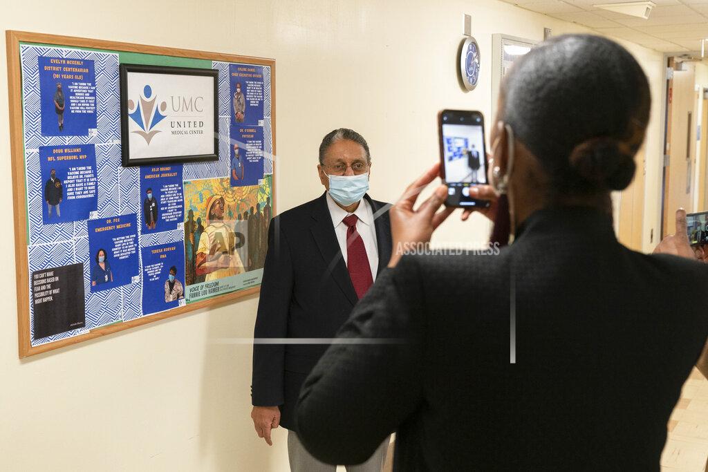 Jacquelyn Martin In this Wednesday, Feb. 10, 2021, photo Wallace Charles Smith, 72, who is a pastor at Shiloh Baptist Church, has his picture taken, by United Medical Center's Vice President of Public Relations Toya Carmichael, at the hospital in southeast Washington. The hospital has a board of quotes and photographs from people who have been vaccinated against COVID-19 to encourage others to receive the vaccine. (AP Photo/Jacquelyn Martin)